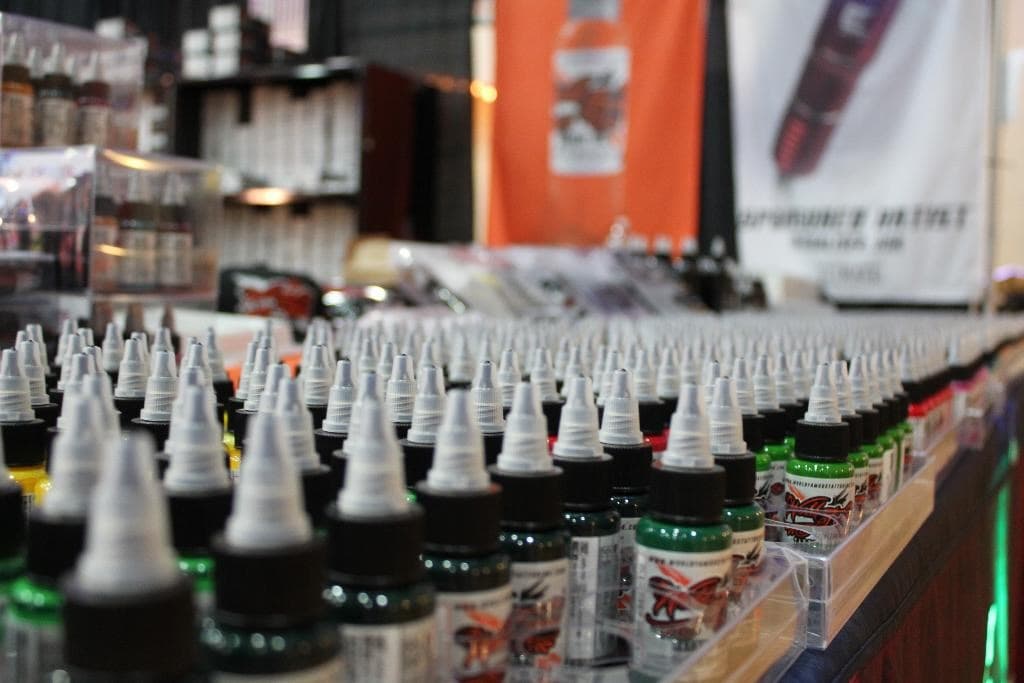 Wall of tattoo ink bottles at a supply convention booth